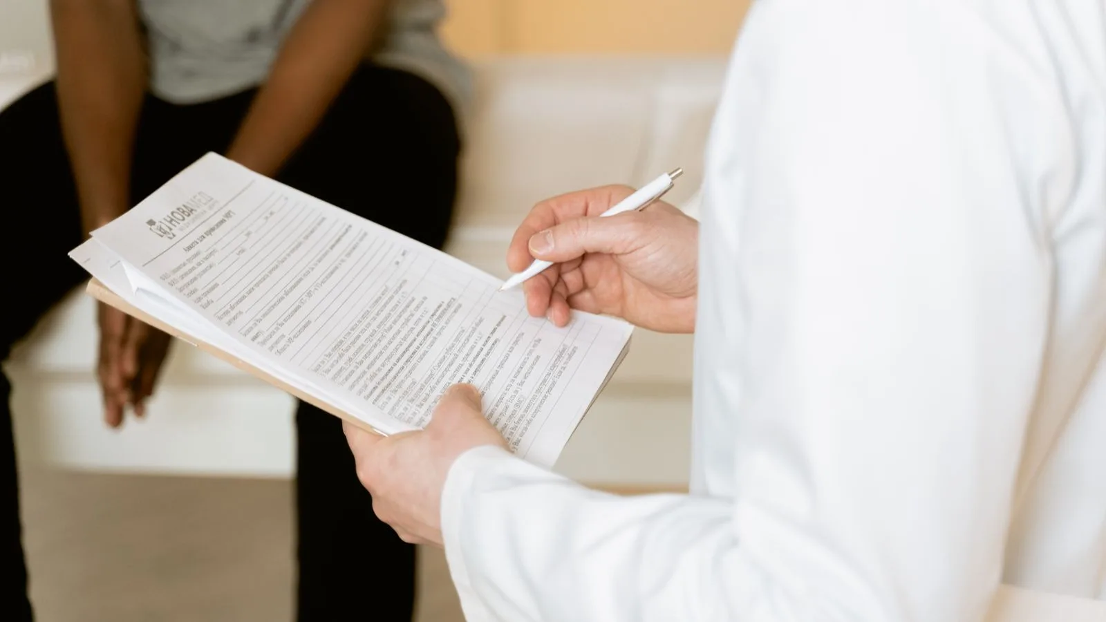 Healthcare professional reviews medical form during patient consultation in a clinic setting.