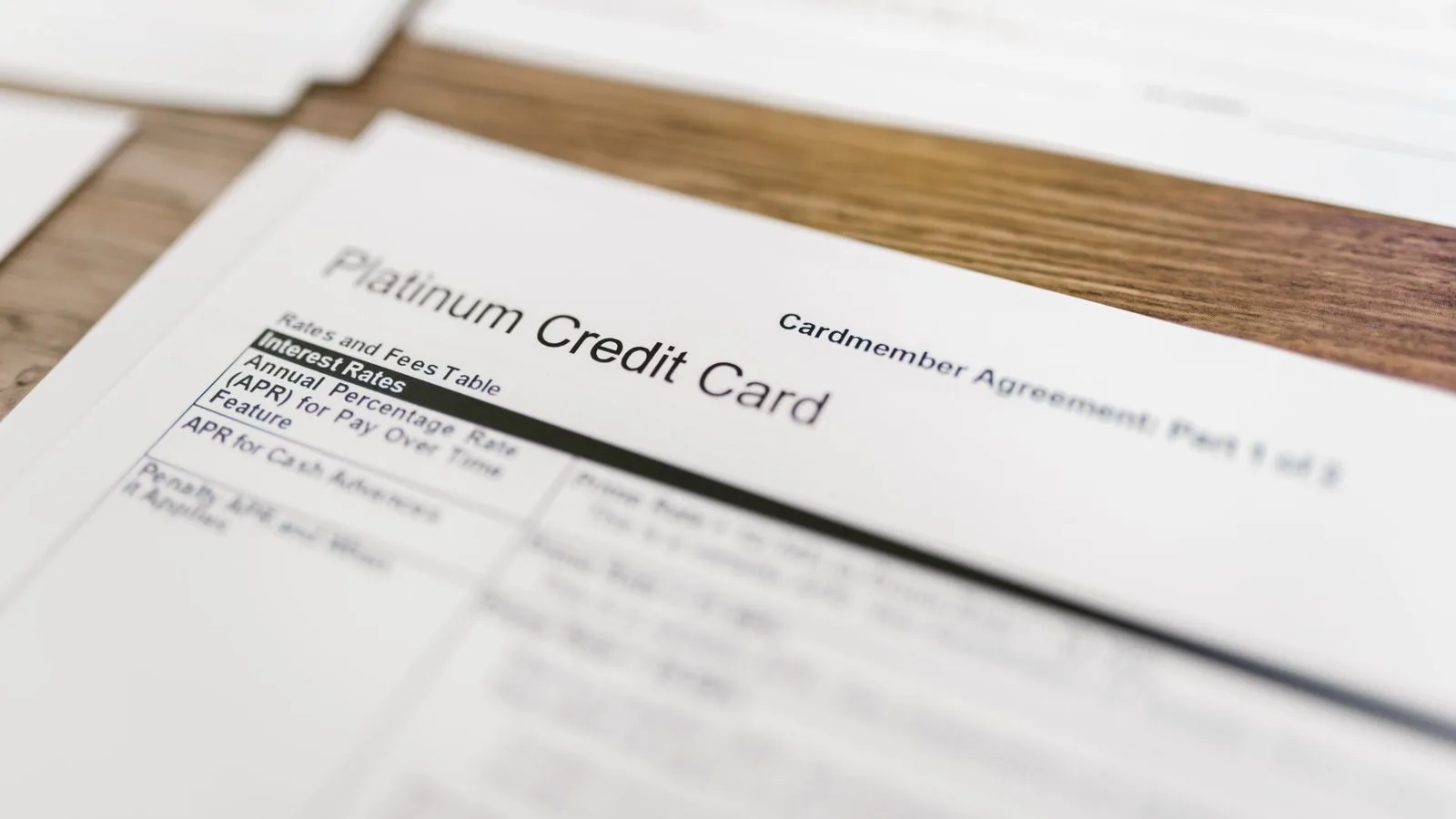 Close-up of a platinum credit card agreement document on a wooden desk.