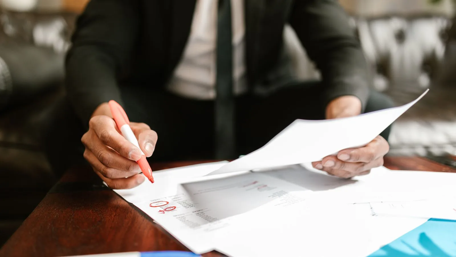 Businessman working with financial documents at office desk, highlighting details.