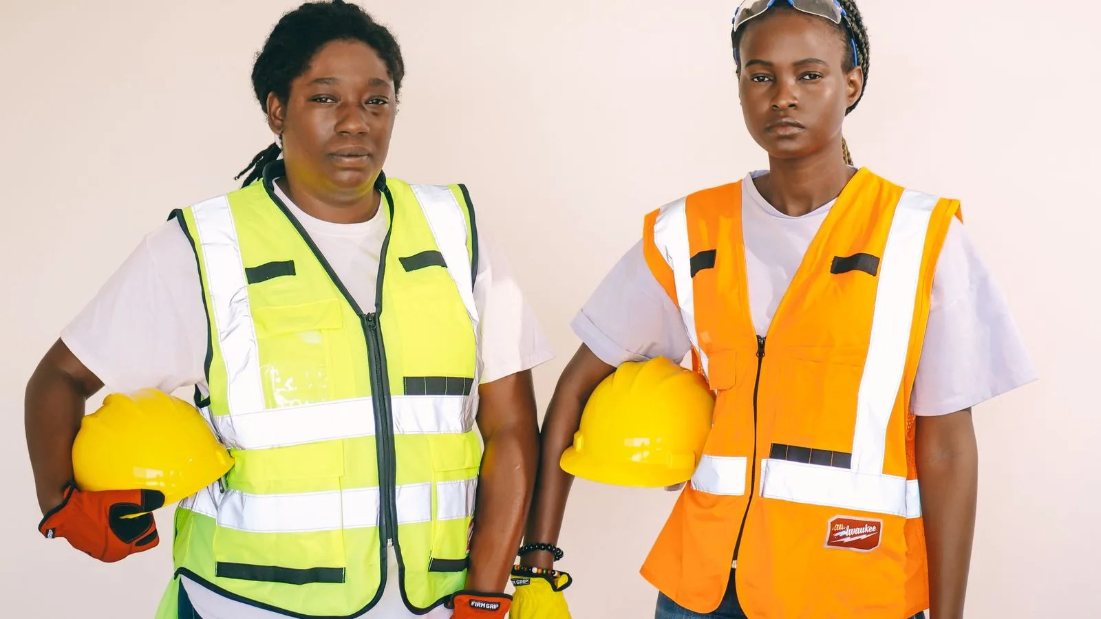 Two women wearing safety vests and helmets at a construction site.